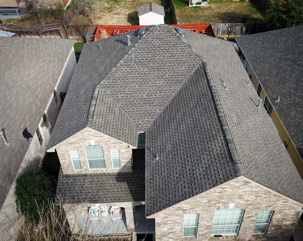 Overhead drone view of a completed grey architectural shingle roof on a two story brick home in San Antonio, showing the ridge, hip and valley lines