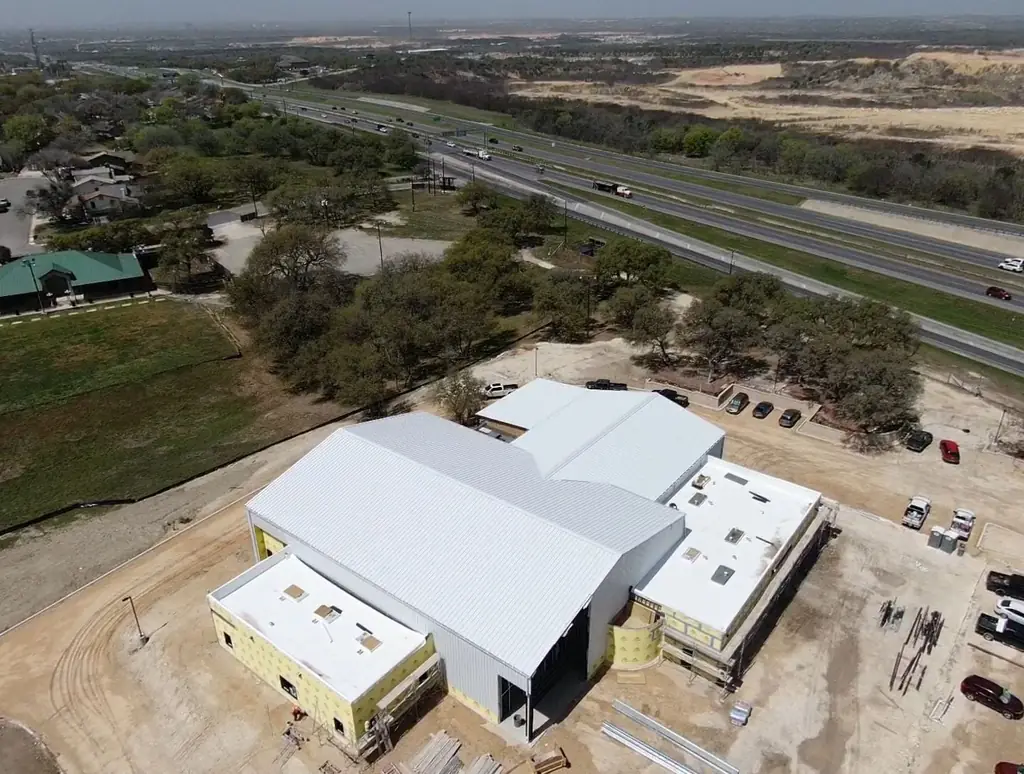 Aerial view of a commercial building in San Antonio part way through a standing seam metal roof installation